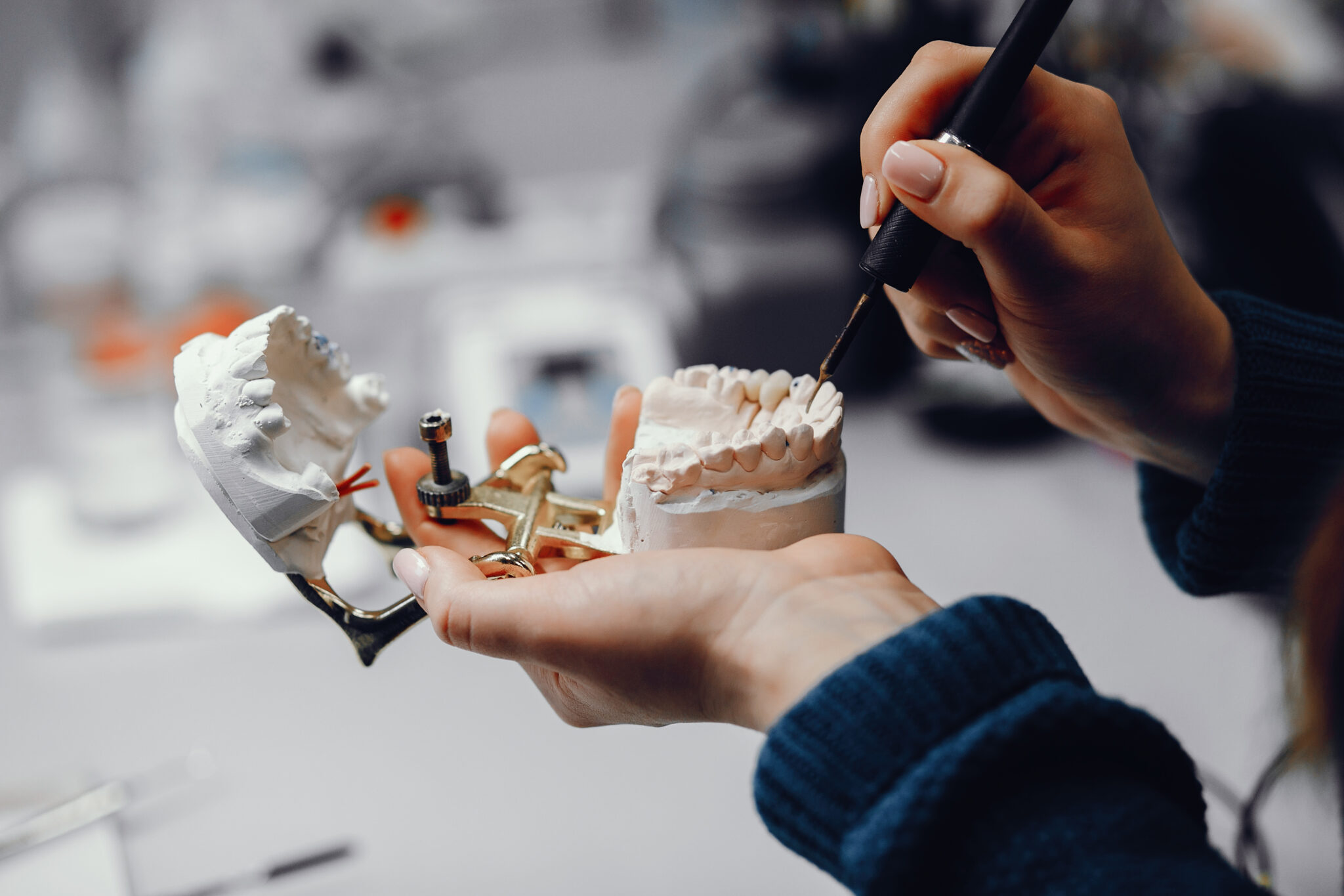 Plastic jaw in the dentist's office. The doctor holds in the hands of dental implants.